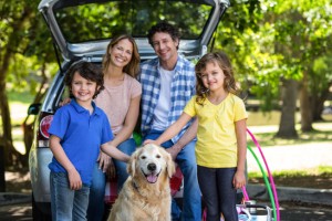 Smiling family in front of a car in the park